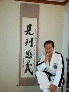 Grandmaster Yoosun Lee with a calligraphy banner that honors his contributions to Taekwon Do